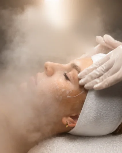 Cliente de olhos fechados com faixa na cabeça recebendo limpeza de pele com vapor na Ellevare